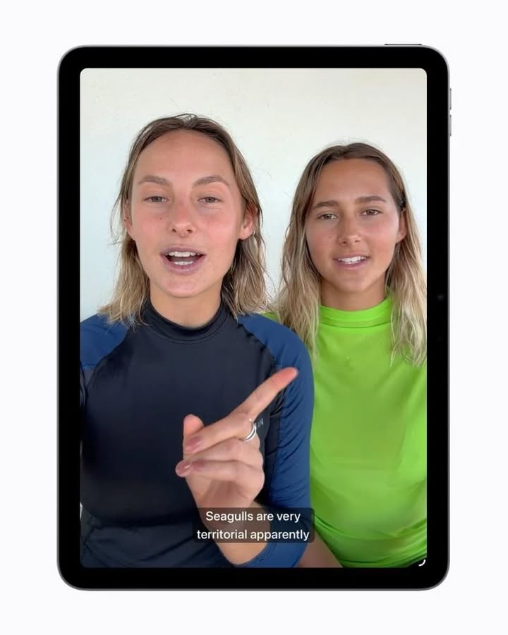 Apple demonstrācija ar automātiski ģenerētiem subtitriem video. iPad ekrānā redzams video ar divām runājošām sievietēm, bet apakšā automātiski parādās subtitri angļu valodā.
